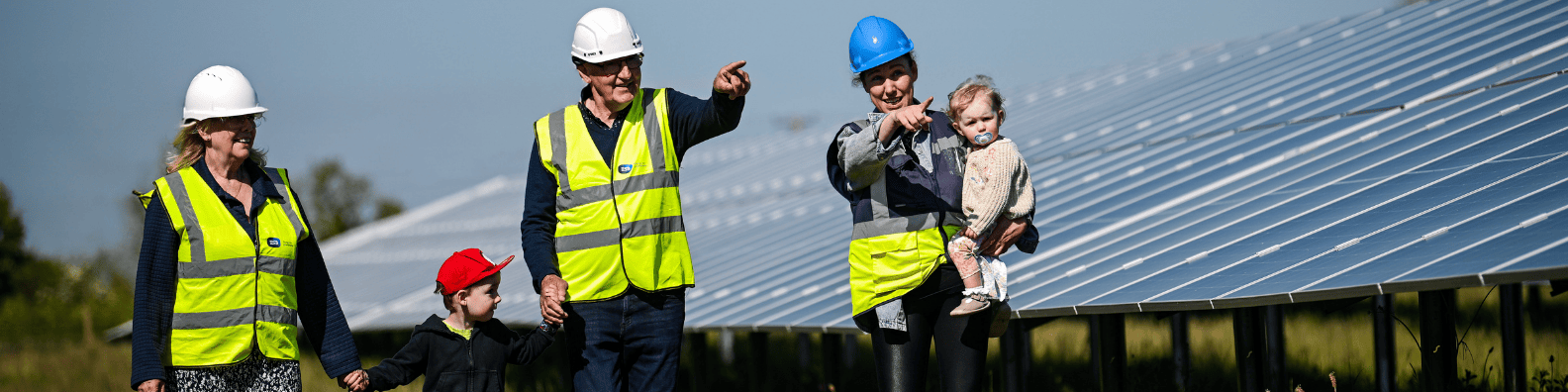 Family with 3 generations at solar farm pointing ahead